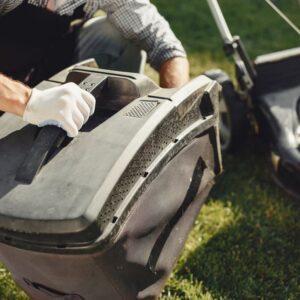 An adult man replacing a lawn mower bag on a sunny day in the yard. - Photo by Gustavo Fring on Pexels