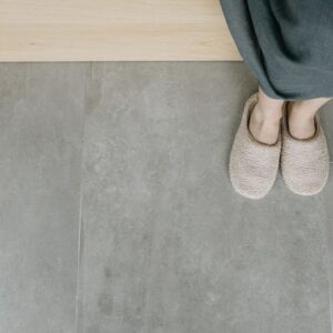 Overhead view of feet in plush slippers on a modern tiled floor, creating a cozy indoor vibe. - Photo by Ivan S on Pexels