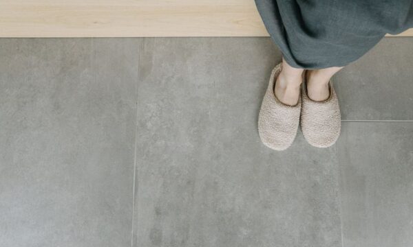 Overhead view of feet in plush slippers on a modern tiled floor, creating a cozy indoor vibe. - Photo by Ivan S on Pexels